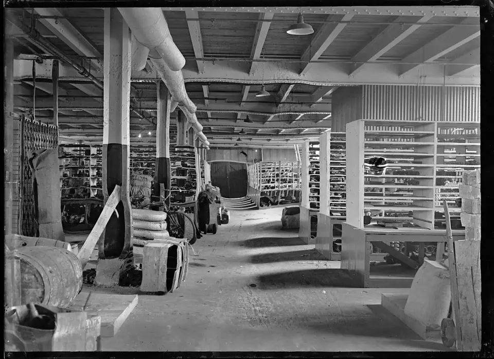 1926 tarihli siyah-beyaz fotoğrafta raflar ve sandıklarla dolu uzun bir demiryolu atölyesi deposu