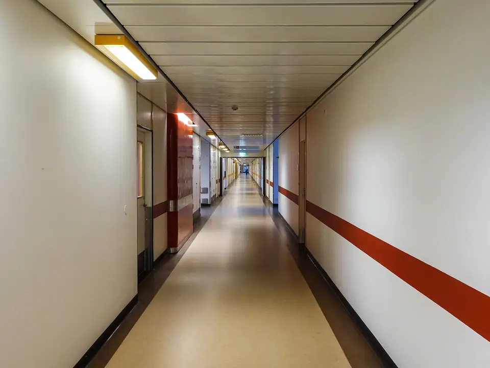 Beyaz duvarlı, kırmızı şeritli uzun ve boş bir hastane koridoru
